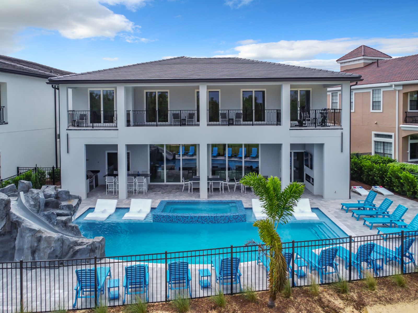 Rear of The Most Fun House, with a pool slide on the left and a spa in the pool.